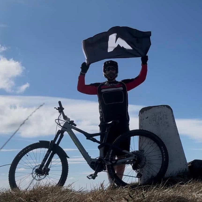 Person with a bicycle holding a flag against a blue sky