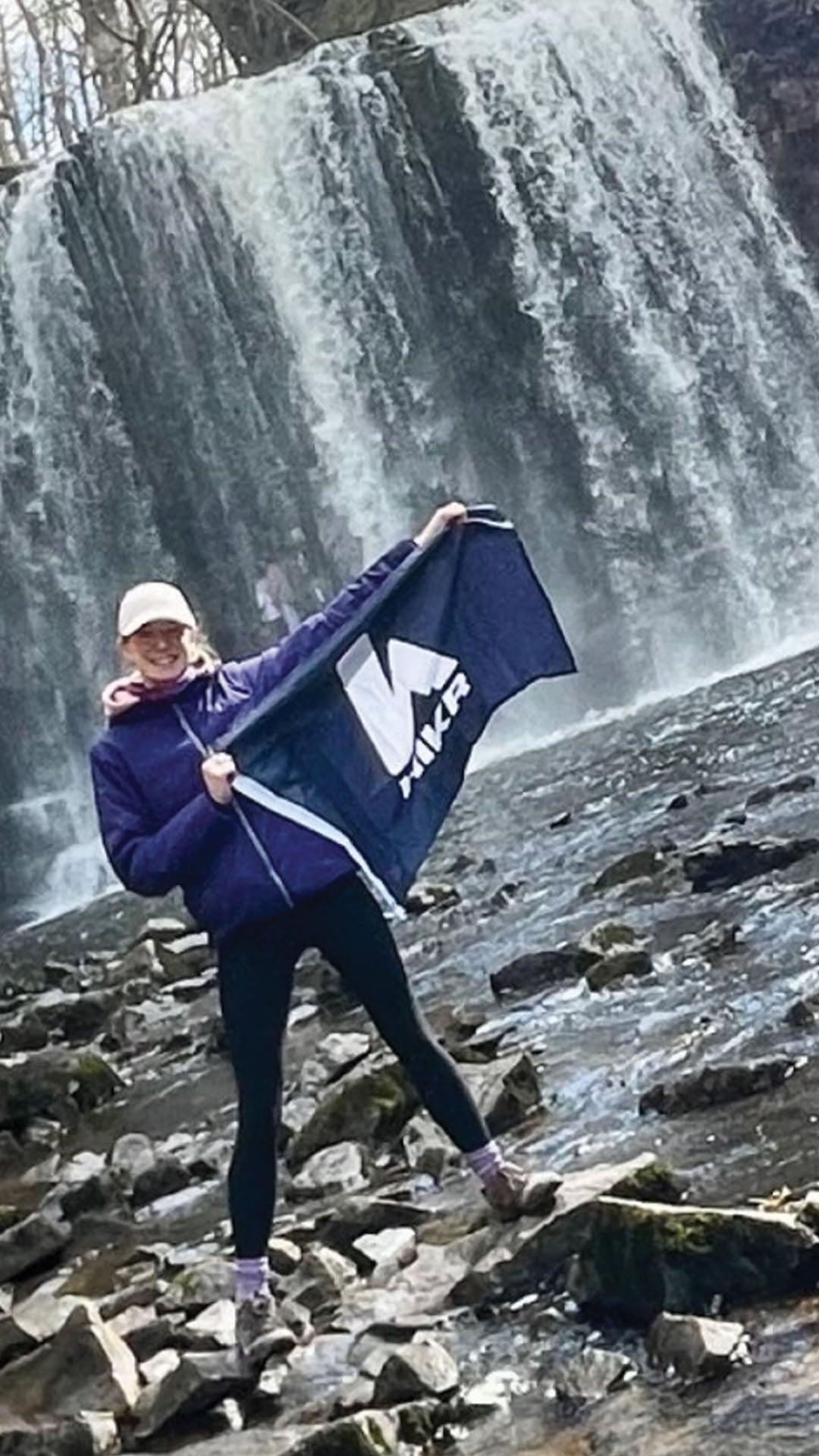Person holding a hikr FLag with a waterfall in the background