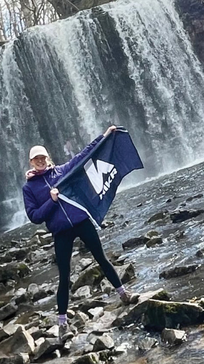 Person holding a hikr FLag with a waterfall in the background