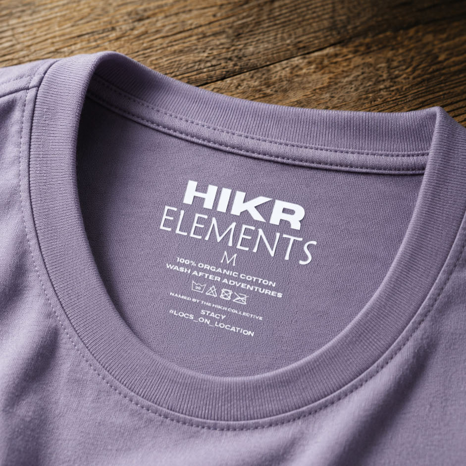 Close-up of a purple t-shirt with 'HIKR ELEMENTS' branding on a wooden surface