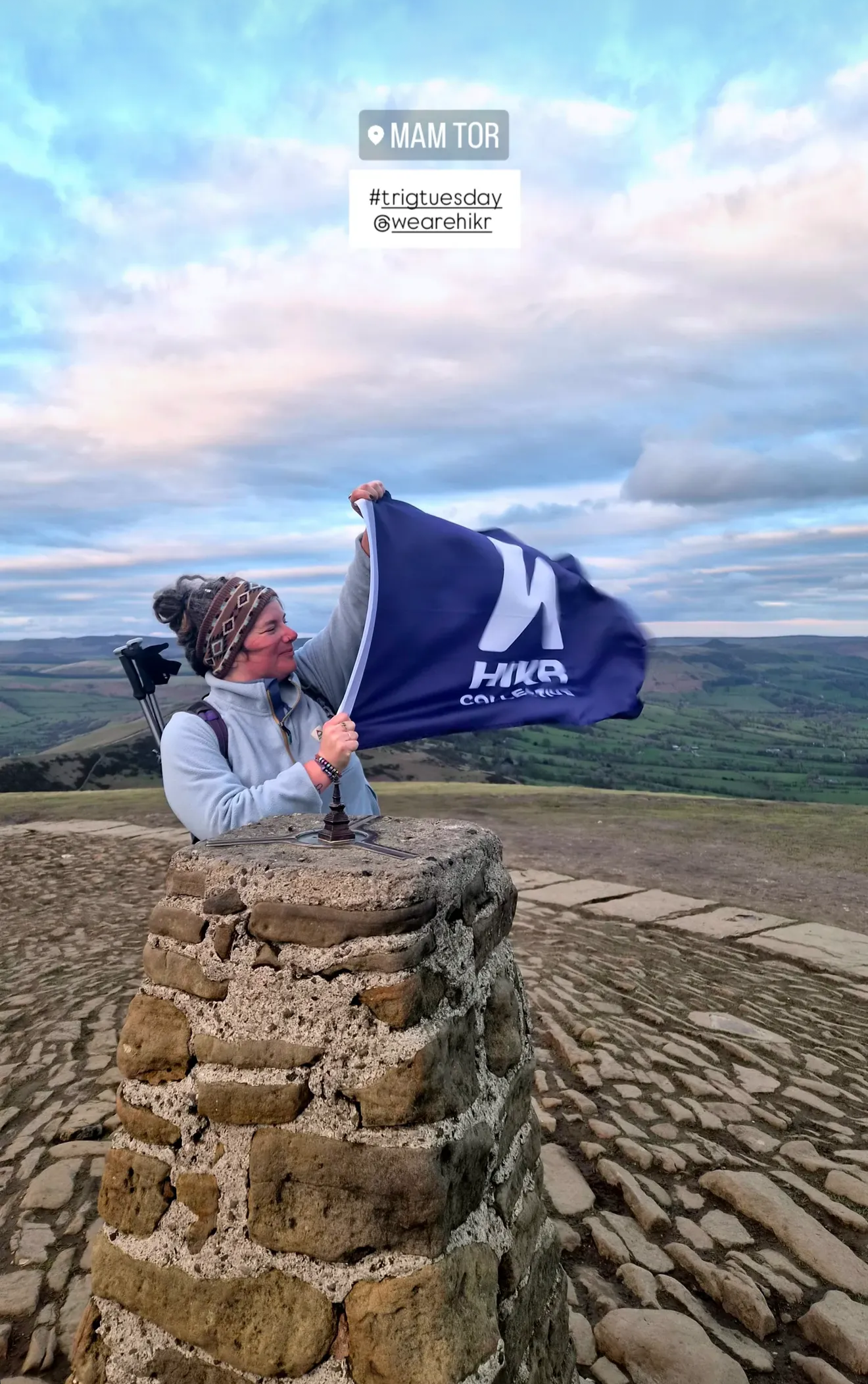 Person holding a HIKR flag on top of MAM TOR with a scenic background