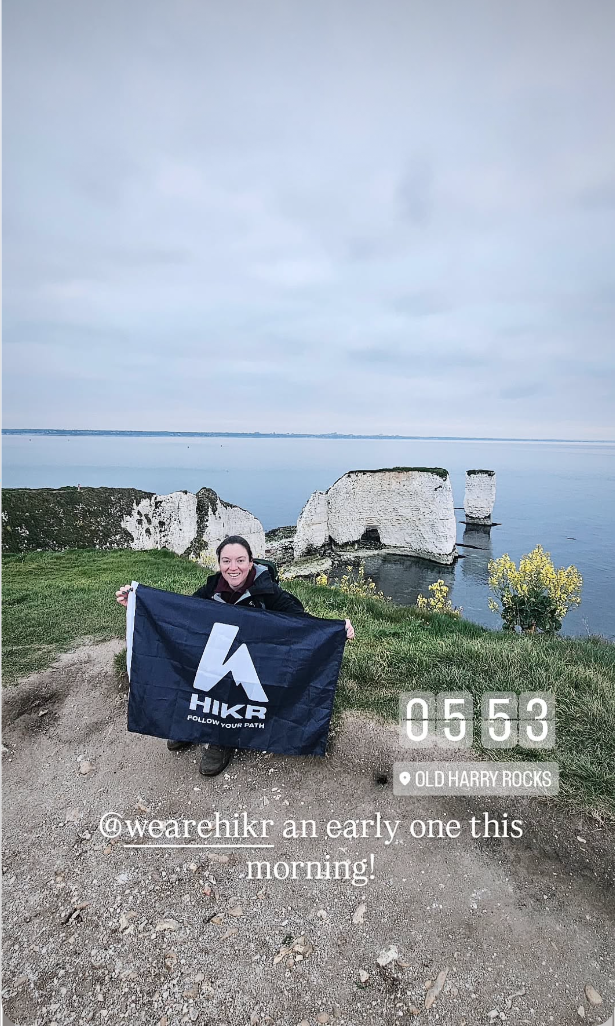 Person holding a HIKR Flag with ruins and ocean in the background